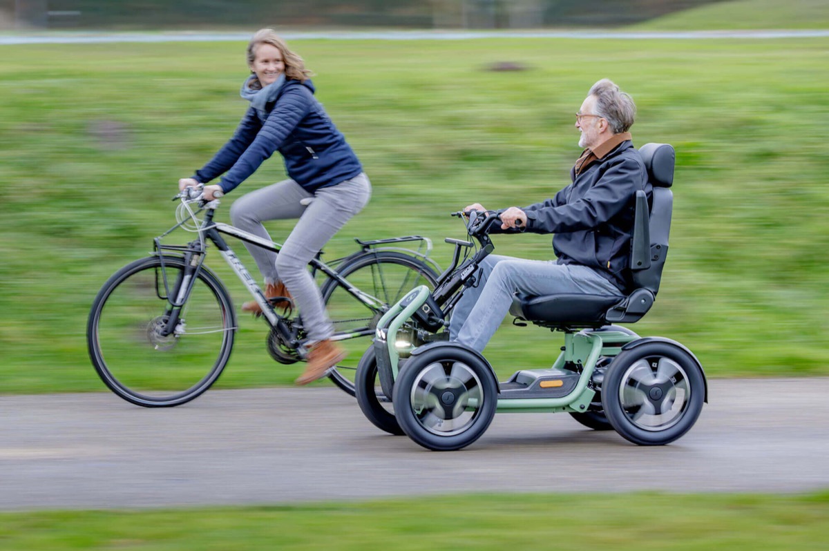 An older woman riding a four-wheel mobility scooter along a coastal footpath on the Bellarine